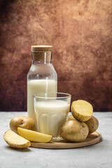 vegan potato milk in glass and raw potato. Alternative plant based milk. superfood concept. Healthy, clean eating. Vegan or gluten free diet. vertical image place for text