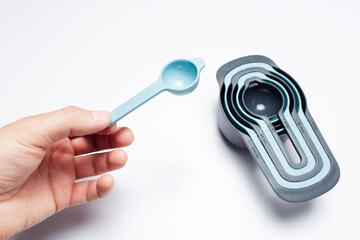 Photo of a hand holding a spoon from the set of measuring cups, kitchen tools.