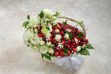 Large basket filled with strawberries, raspberries, blueberries, cherries, decorated with white flowers and mint leaves