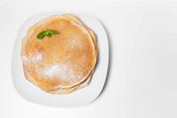 Top view of vegan thin pancakes, on the white plate, decorated with mint leaf.