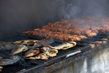 A lot of various fish is prepared on a large grill for a large party