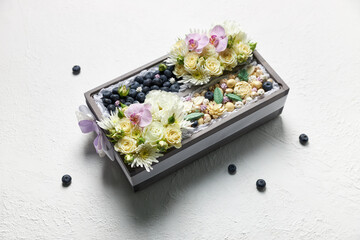 Wooden box filled with berries and chocolate sweets decorated with white flowers
