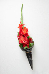 Bouquet of red gladioluses, red pepper, decorated with bay leaves and broccoli on a white background