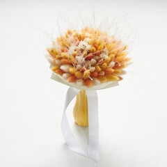 Small bouquet of white and orange laguruses, standing in a vase on a white background