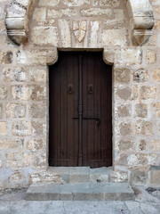 Old brown wooden door with a massive locking gear in a stone wall