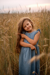 girl is standing  in a wheat field and smiling