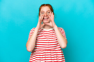 Young reddish woman isolated on blue background shouting and announcing something