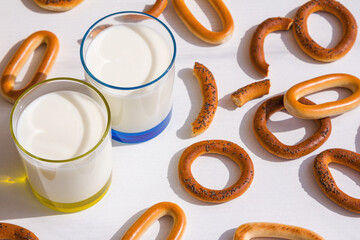 Fresh milk in glasses and bagels with poppy seeds on a table. 