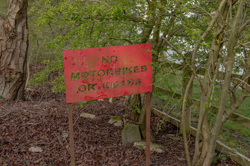 Red metal sign saying no motorbikes or quads