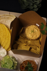 Mexican food, guacamole, chilli, nachos, cheddar, sour cream, tacos, lettuce, avocado, tomato salad, burritos wrap tortilla lime salsa coriander catus capsicum chili pepper onion takeaway delivery box