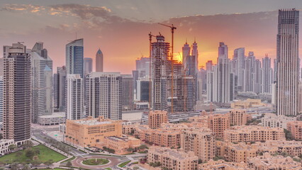 Naklejka premium Dubai's business bay towers at sunset aerial timelapse. Rooftop view of some skyscrapers