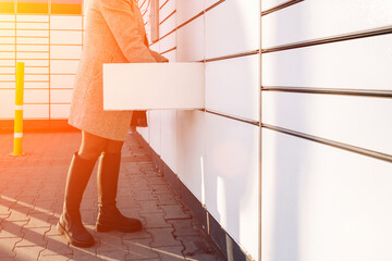 Pickup parcel. Courier box in woman hands at post delivery automat terminal. Self service post...