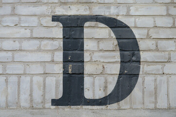 Black letter D painted to brick wall on gray background  (from a letter set containing B, C, D, F,...