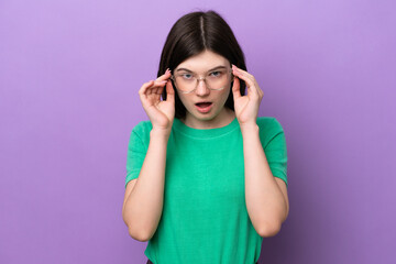 Young pretty Russian woman isolated on purple background With glasses and surprised expression