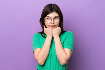 Fototapeta premium Young pretty Russian woman isolated on purple background With glasses and tired