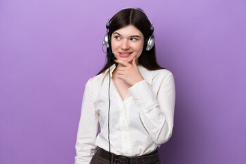 Telemarketer Russian woman working with a headset isolated on purple background looking to the side