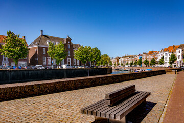 Beautiful alley by the water canal in perspective, houses facade in line, sitting bench for rest