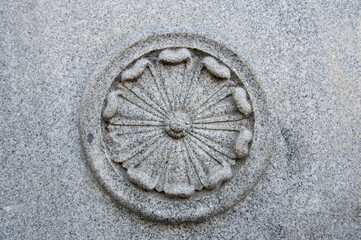 circular decorative element with a flower in granite stone on the facade of a building