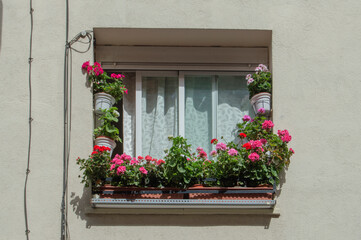 Fototapeta na wymiar an isolated window with pots with red and fuchsia geraniums