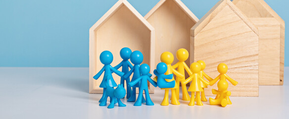 Concept of ukrainian families searching shelters. Yellow and blue dolls in front of wooden houses....