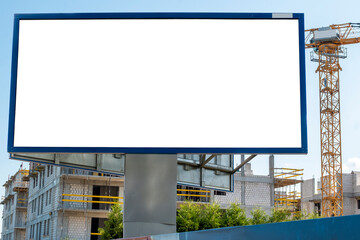 Blank white billboard for advertisement near the construction site with tower cranes