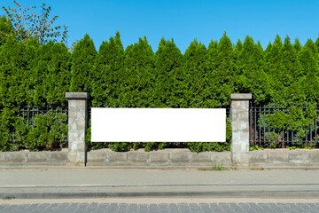 Blank white advertising banner on the fence of city park