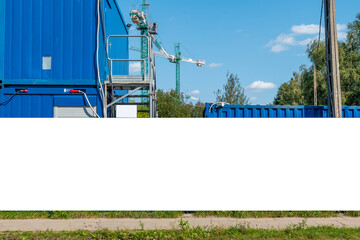 Advertising banner mock-up on the fence of construction site in front of blue construction barracks © diesirae