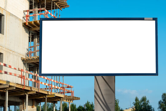 Blank white advertising billboard in front of the building under construction