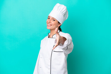 Young caucasian chef woman isolated on blue background shaking hands for closing a good deal