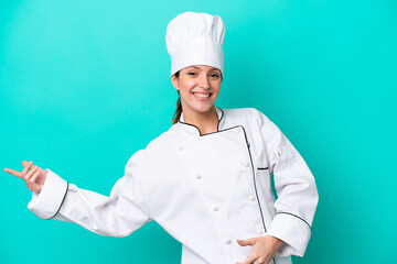 Young caucasian chef woman isolated on blue background making guitar gesture