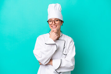 Young caucasian chef woman isolated on blue background with glasses and smiling