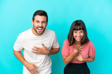 Young couple isolated on blue background smiling a lot while putting hands on chest