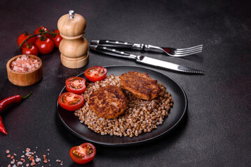 Delicious fresh boiled buckwheat porridge with vegetables and spices on a black plate