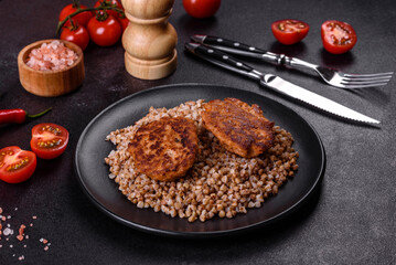 Delicious fresh boiled buckwheat porridge with vegetables and spices on a black plate