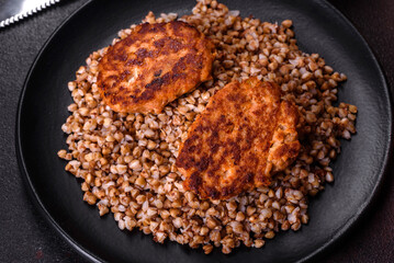 Delicious fresh boiled buckwheat porridge with vegetables and spices on a black plate