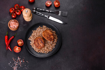 Delicious fresh boiled buckwheat porridge with vegetables and spices on a black plate