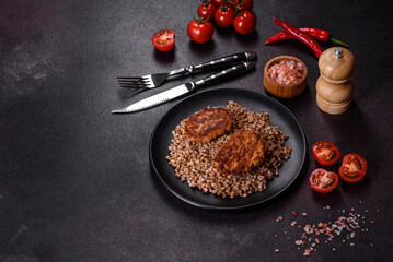 Delicious fresh boiled buckwheat porridge with vegetables and spices on a black plate