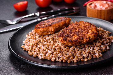 Delicious fresh boiled buckwheat porridge with vegetables and spices on a black plate