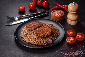 Delicious fresh boiled buckwheat porridge with vegetables and spices on a black plate