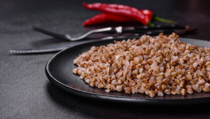 Delicious fresh boiled buckwheat porridge with vegetables and spices on a black plate