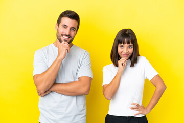 Young couple isolated on yellow background smiling and looking to the front with confident face