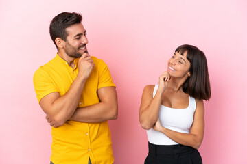 Young couple isolated on pink background looking looking at each other
