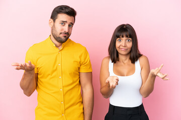 Young couple isolated on pink background unhappy and frustrated with something because not understand something