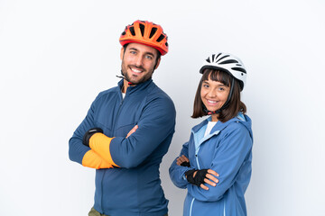 Young cyclist couple isolated on white background keeping the arms crossed in lateral position while smiling