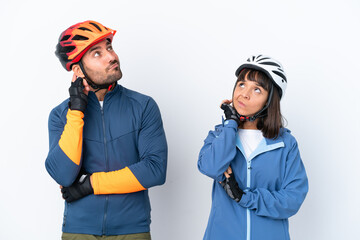 Young cyclist couple isolated on white background thinking an idea while scratching head