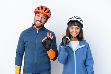 Young cyclist couple isolated on white background showing an ok sign with fingers