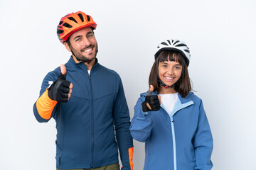 Young cyclist couple isolated on white background giving a thumbs up gesture because something good has happened