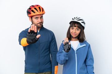 Young cyclist couple isolated on white background making stop gesture denying a situation that...