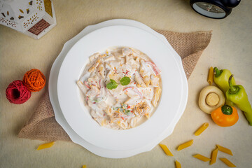 Creamy white dipped pasta in a plate top view on wooden background