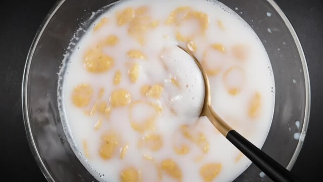 Plate of milk with wheat flakes, eat with a spoon. olly slider close up. Slow motion